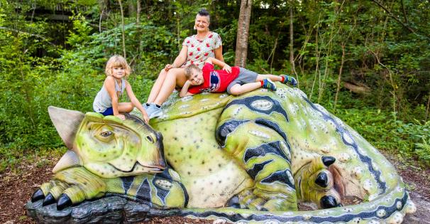 Family sits atop a green dinosaur sculpture