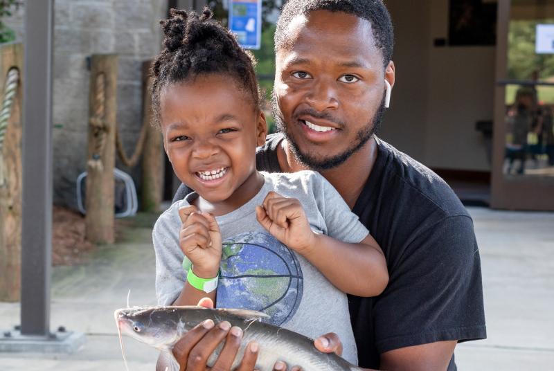 Parent and child pose with catfish at Fishing Rodeo