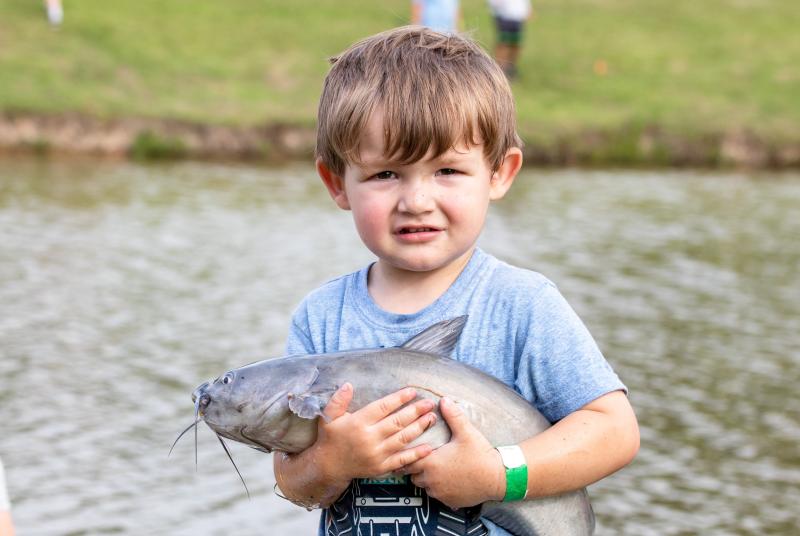 Boy holds catfish at a Youth Fishing Rodeo event