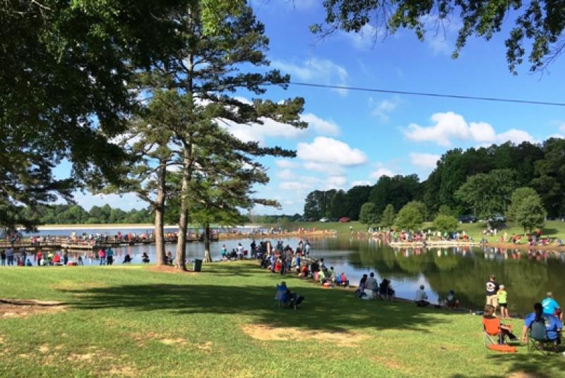 Crowd around a pond at a Youth Fishing Rodeo event